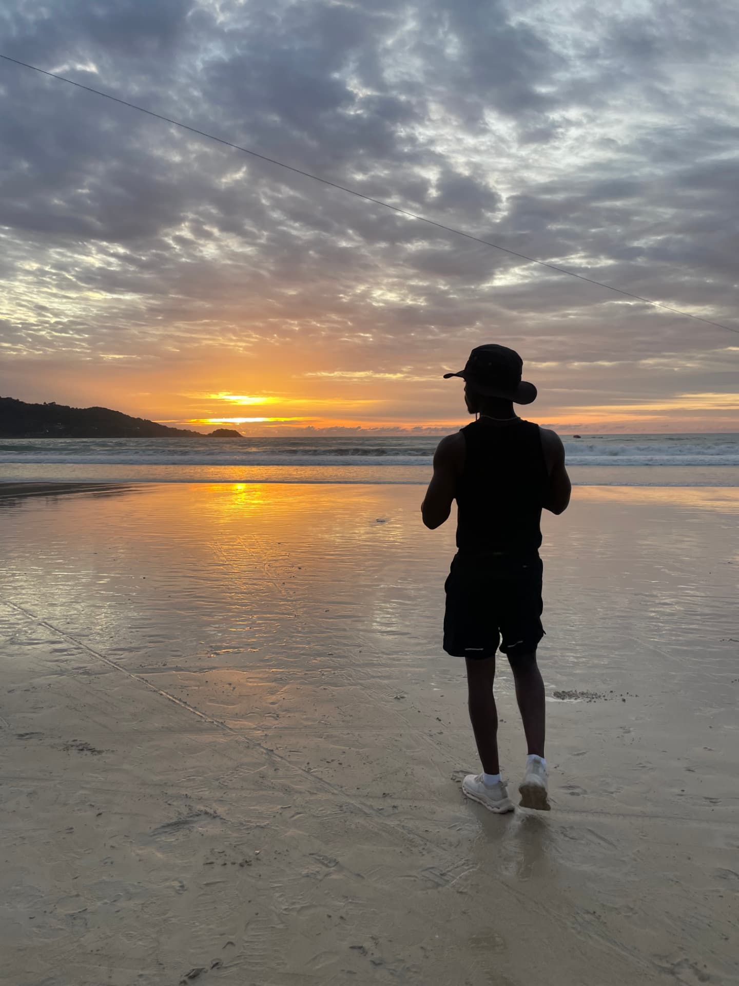 Standing on wet sand watching an orange sunset over the ocean